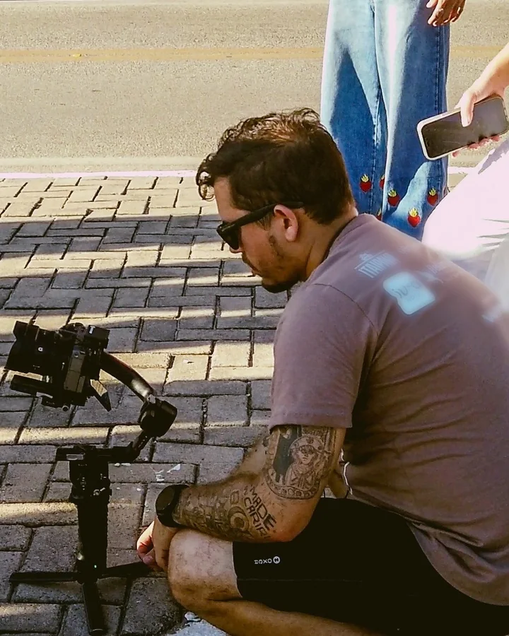 Operador da Codec agachado com o gimbal, numa gravação na rua