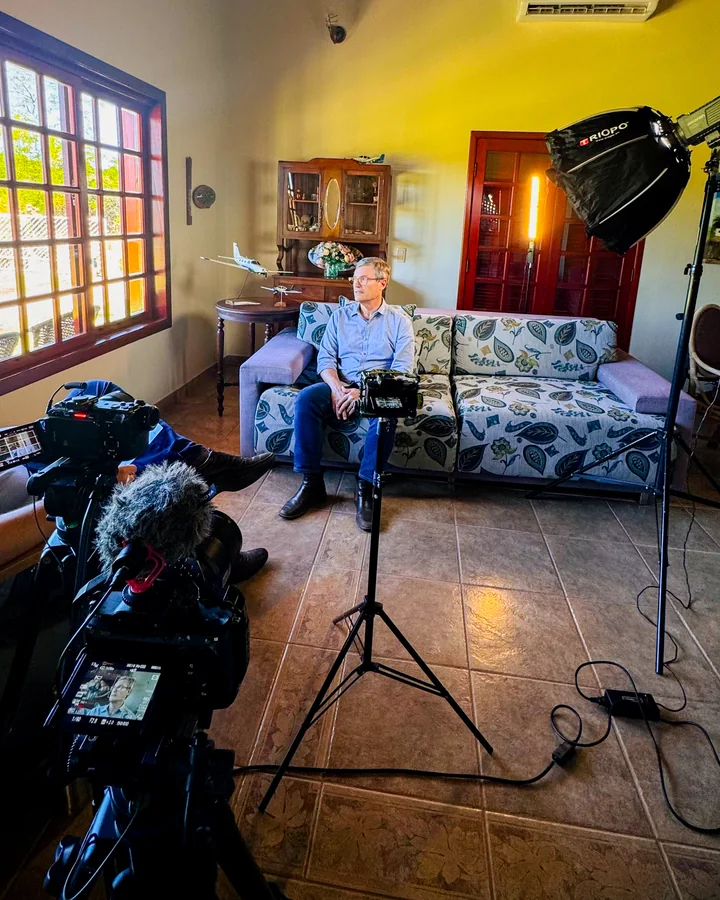 Set de entrevista com a câmera em primeiro plano e o entrevistado no sofá