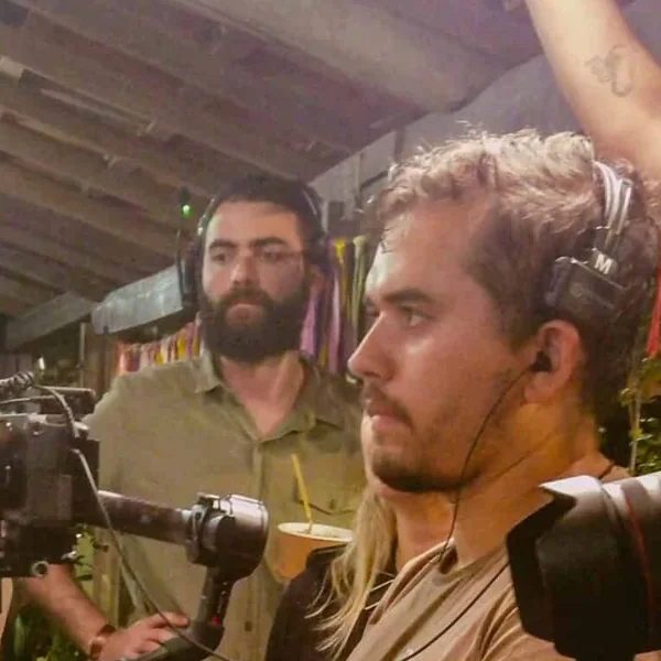 Dois operadores da Codec com fone, e a câmera no estabilizador, numa gravação à noite