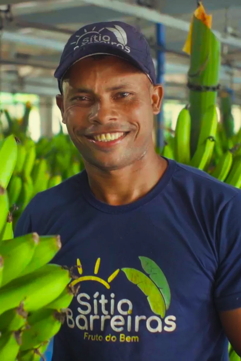 Colaborador sorrindo entre cachos de banana, em filme institucional da Codec