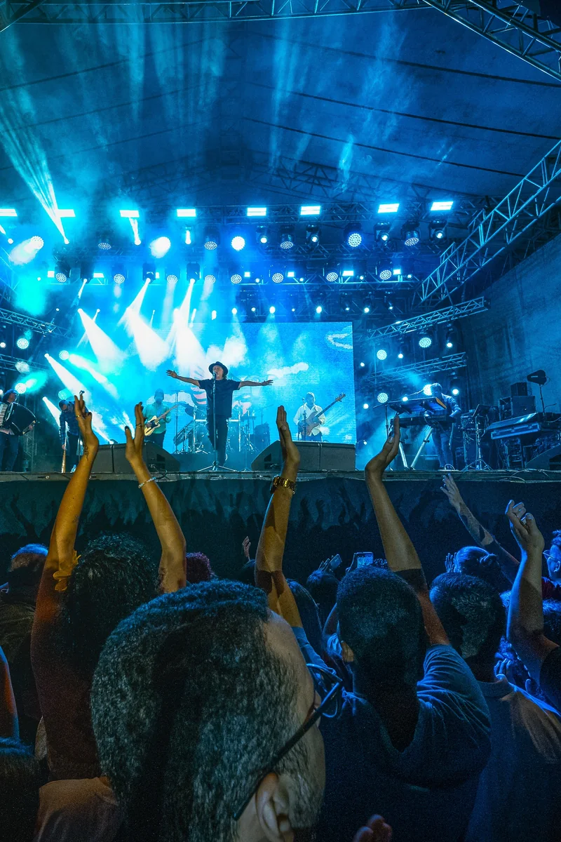 Público de braços erguidos diante do palco iluminado, em cobertura de evento da Codec